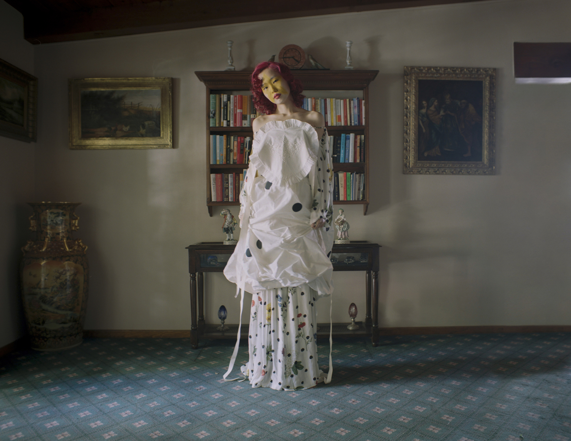 A model with yellow star makeup in a white dress standing in a study